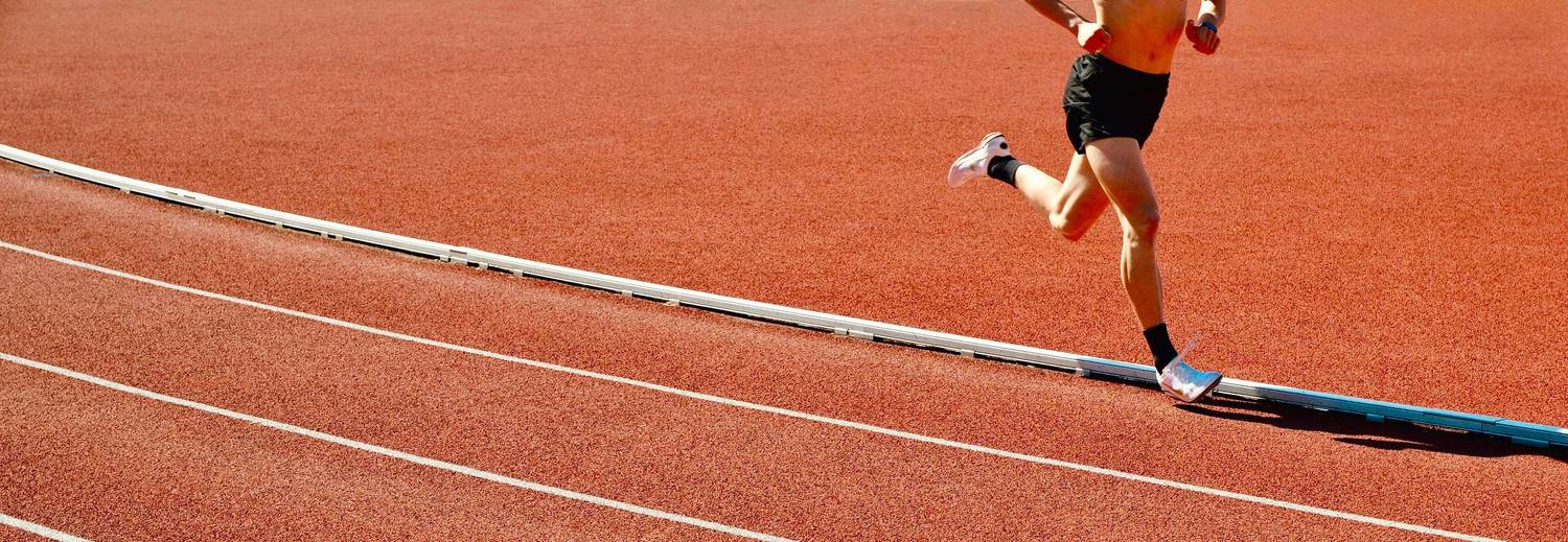 A runner on a red athletics track with white lane lines